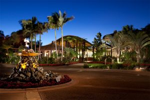 Exterior of Paradise Point Resort & Spa at dusk with palm trees, tropical landscaping, and illuminated entrance fountain.
