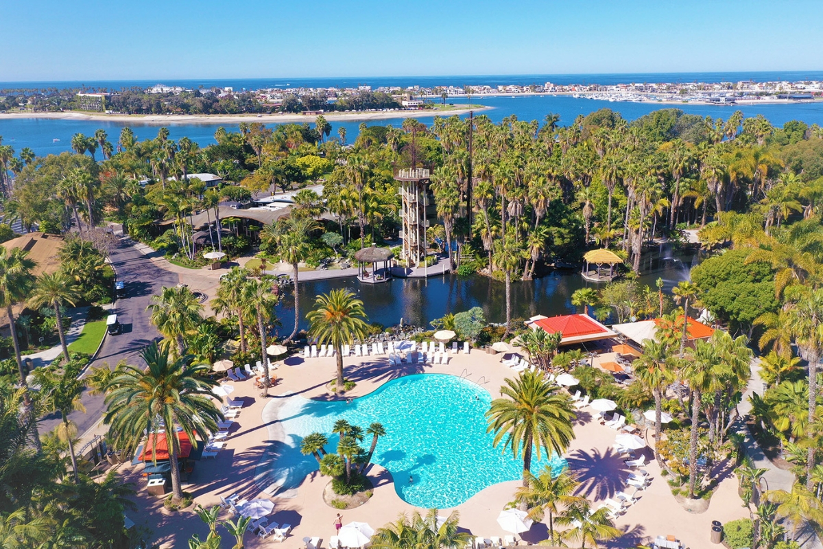 Aerial view of Paradise Point Resort & Spa featuring a lagoon-style pool, tropical palm trees, and Mission Bay waterfront in San Diego.